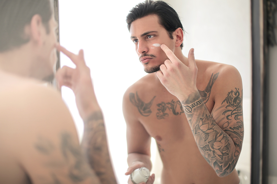 Hombre aplicándose crema facial. belleza hombres