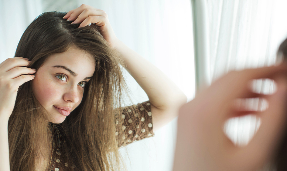 Imagen de chica joven observando su cabello para ilustrar el artículo sobre porqué se cae el pelo en otoño