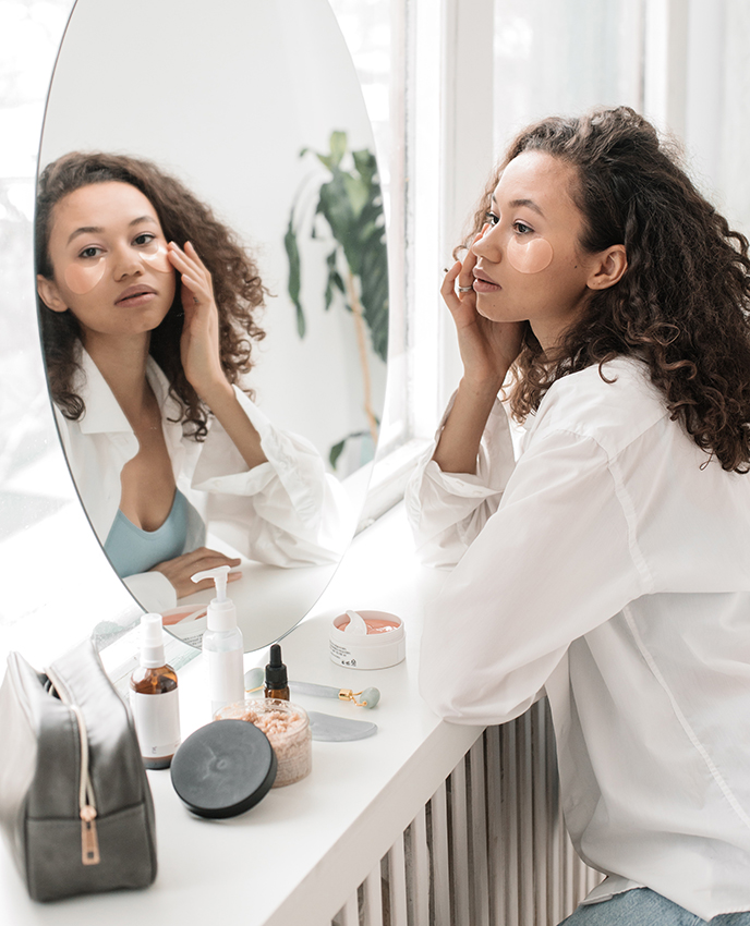 Mujer en un tocador, aplicándose parches para contorno de ojos. Imagen para el post: consumidor de belleza durante 2020